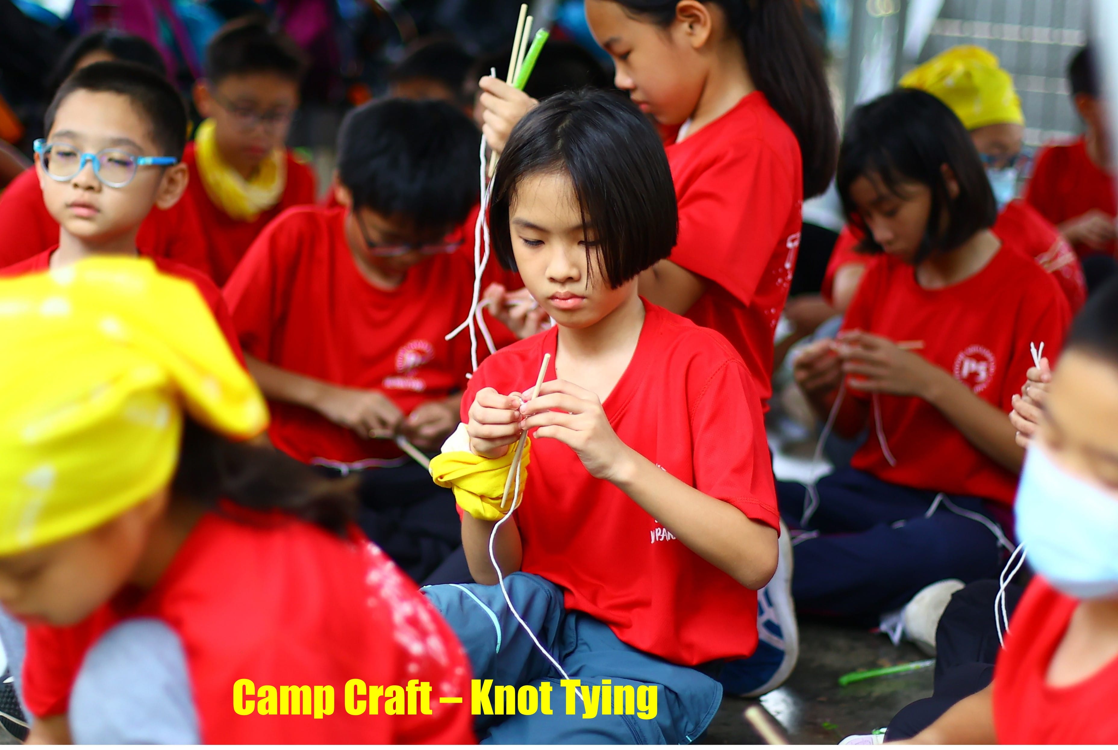 A P5 girl is involved in camp craft of knot tying